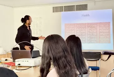 People looking at projector screen as person gives talk