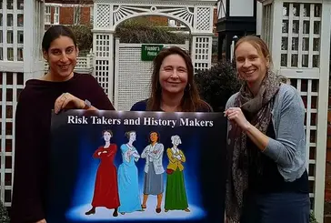 Three women holding a sign