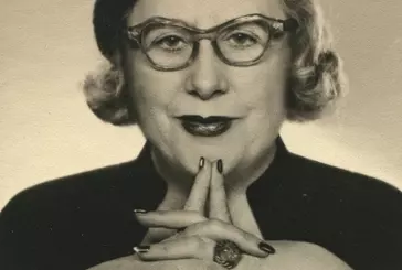 Sepia photo portrait of Dorothy Wilding wearing a beret and glasses.