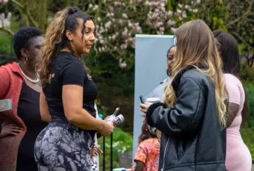 Photograph of women holding a mic speaking to another women in a park