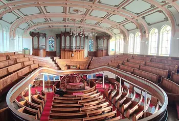 A large room containing a pipe organ and two levels of wooden seating