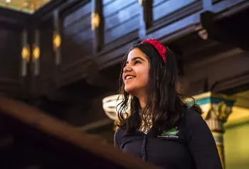 A young child in a school uniform looking up and smiling inside a synagogue 