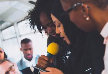 Young people reading poetry around a microphone