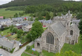 A drone photograph of the church of St. Margaret's, nestled between houses and lush green fields.