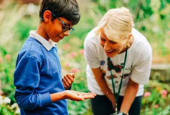 A boy holds a moth with a woman smiling at him
