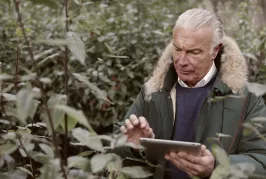 Man using tablet surrounded by plants 