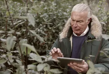 Man using tablet surrounded by plants 