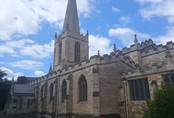 A village church with a tall with a hexagonal spire.