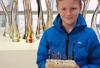 A young person holds their artwork as part of the exhibition.