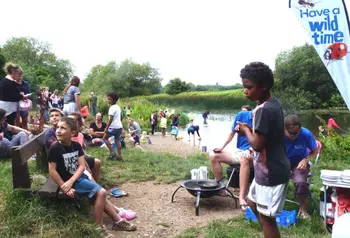 A group of children and adults doing outdoor activities by a river