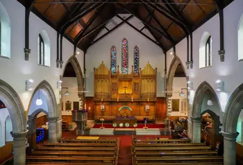 An elevated view across the pews of St. Andrew's, towards the large organ and stained glass windows.