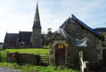 Tŷ’r Meirw Bochrwyd gydag Eglwys Sant Cynog yn y cefndir 