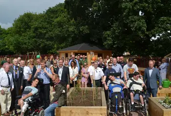 People gather around the raised beds in the community garden