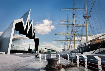 A view of the facade of the Riverside Museum in Glasgow, opposite a docked tall ship in the Clyde.
