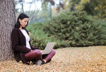 Digital guides - online security and privacy A young woman using a computer laptop under a tree