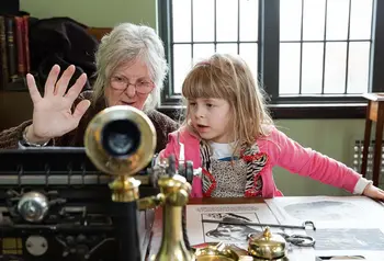 A person teaching a young child about past events and showing them an old type writer