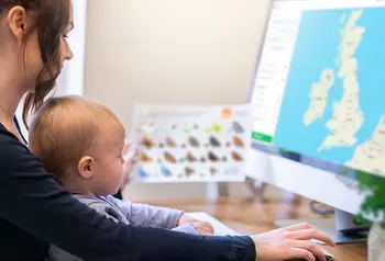 Adult and baby in front of computer showing map of UK
