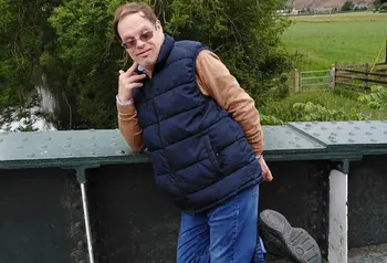 A man standing on one leg on a bridge