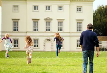 Three children and one adult approach historic house