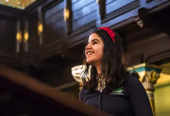  A young child in a school uniform looking up and smiling inside a synagogue 