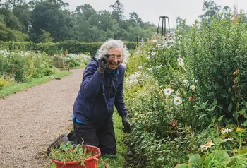 Person kneeling in outdoors space whilst smiling