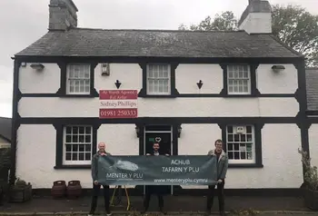 Dau berson yn sefyll y tu allan i adeilad