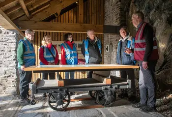 A group of people in high-vis standing around a table converted from an old railway wagon