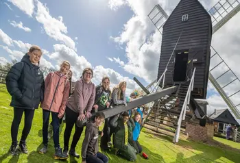 A group of children leading on a piece of wood attached to a windmill.