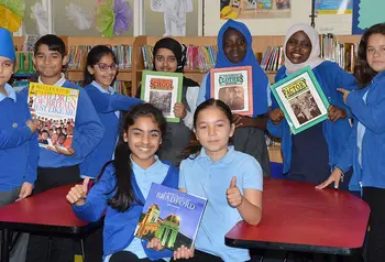 Group of children hold books whilst looking at the camera