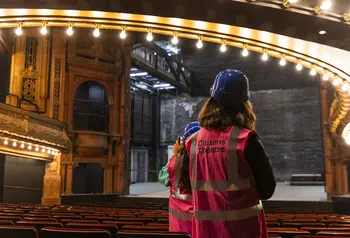 Two people in high vis jackets and hard hats explore the restored auditorium.