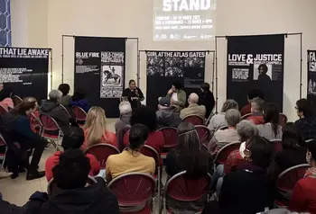 A photo of an indoor event, with a speaker talking to a seated audience