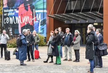 A group of 13 people standing outside a building listening to a tour guide as part of a community walking tour
