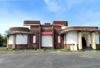 The art deco red brick structure of the Iron Duke, with its windows boarded up and with visible damage to the facade.