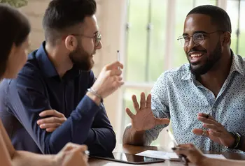 Three people sitting around a table discussing ideas