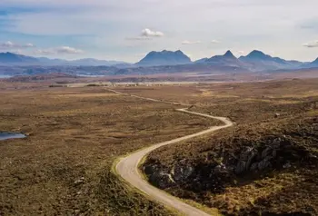 A vast landscape view with a path in the foreground leading into the distance, and mountains along the horizon
