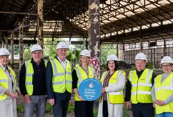 A group of people in hard hats and hi-vis jackets standing under Glasgow Meat Market's historic sheds.