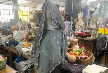 A mannequin with a Sari draped around is standing in a textile workspace