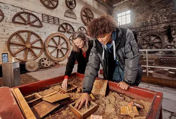Two people do an activity in the foundry building, a large brick industrial building at the National Slate Museum in Wales