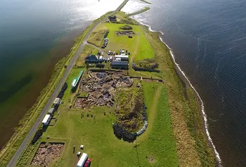 Looking South East over the site, a finger of grass covered land with water either side and a thin causeway visible at the top of the image. Trench J in bottom left; Trench P in centre, and Trench T in distance 