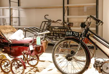 A space in the open store, containing a vintage motorcycle and pram.