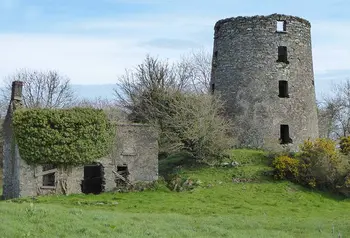 a ruined stone windmill building in the countryside