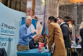 A Heritage Fund member of staff talks with two people at a stall inside a large church
