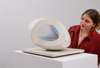 A young woman looks at a sculpture by Barbara Hepworth.