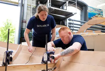 Two Skylark IX volunteers work on building a wooden rowing boat 