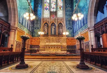 An interior view of a church altar with stained glass windows in the background