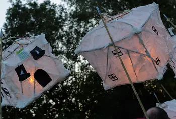 Two paper lanterns in the shape of houses in an outdoor parade