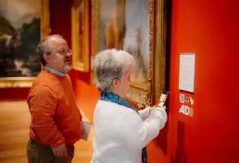 Two visitors use a smart phone to scan a QR code that unlocks additional interpretation and audio guides about the Scottish national collection.