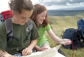 Two people looking at a map and compass in the hills