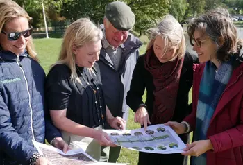 Five people in a park looking at plans on A3 size paper