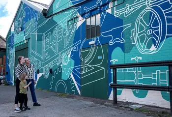 Three people standing in front of a wall painted with a mural in green and blue colours